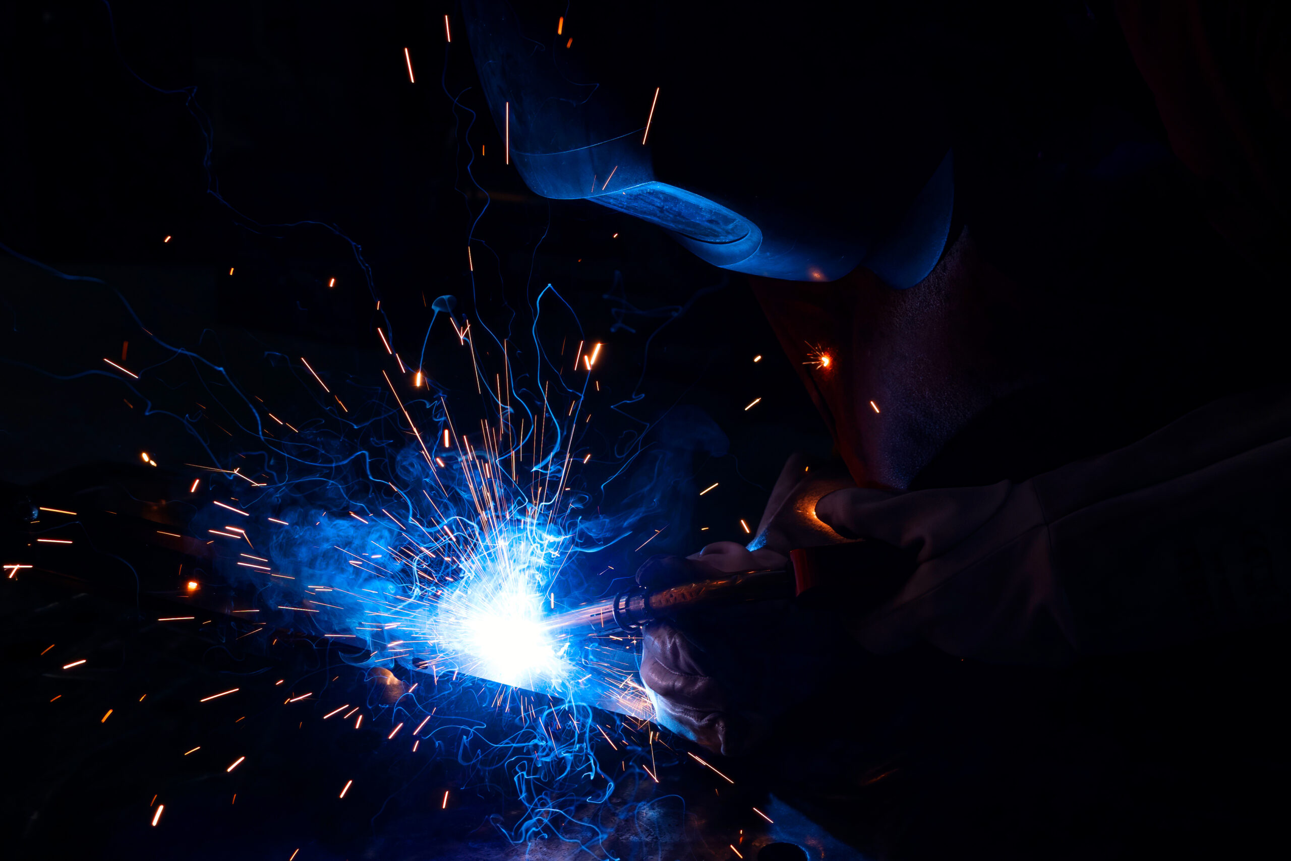 Accueil : soudeur entrain de souder, avec des étincelles et un casque de soudure